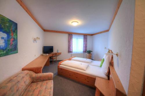 a room with a bed and a couch and a television at Hotel Kuchalber Hof in Donzdorf