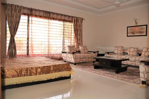 a living room with a bed and chairs and a window at House of Traditions - Family Suite in Islamabad