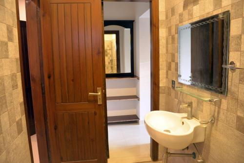 a bathroom with a sink and a toilet and a door at House of Traditions - Family Suite in Islamabad