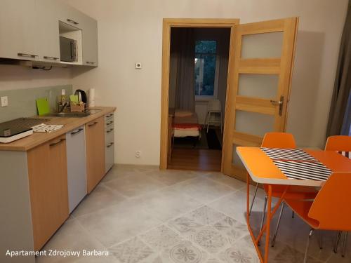 チェホチネクにあるApartamenty Zdrojoweのキッチン(オレンジの椅子、テーブル、ドア付)