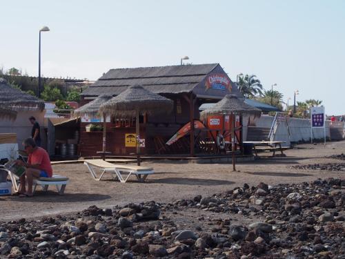 a man sitting on a bench in front of a building at Maravilloso y tranquilo alojamiento en el Palm-Mar in Palm-mar