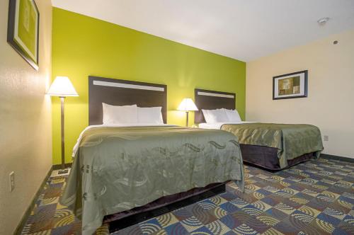two beds in a hotel room with green walls at Quality Inn & Suites Glenmont - Albany South in Glenmont