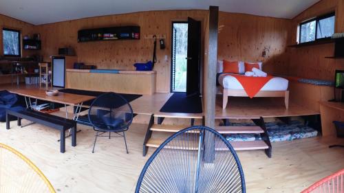 a living room with a table and chairs and a bedroom at BAY OF FIRES ECO HUT off grid experience at Binalong Bay in Binalong Bay