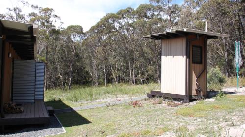 a smallshed next to a house in a field at BAY OF FIRES ECO HUT off grid experience at Binalong Bay in Binalong Bay