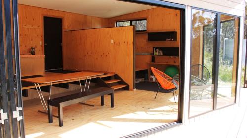 a room with a wooden table and a desk at BAY OF FIRES ECO HUT off grid experience at Binalong Bay in Binalong Bay