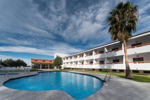 a swimming pool in front of a building at Hotel Pradillo Conil in Conil de la Frontera