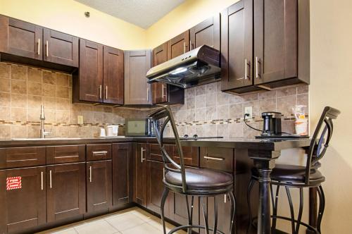 a kitchen with wooden cabinets and a bar with stools at Quality Inn & Suites Glenmont - Albany South in Glenmont