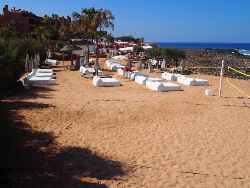 a sandy beach with white lounge chairs and the ocean at Maravilloso y tranquilo alojamiento en el Palm-Mar in Palm-mar