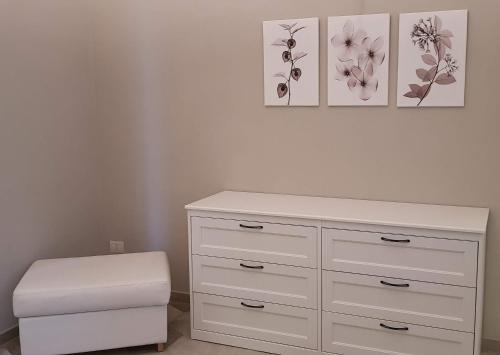 a white dresser with a stool and three pictures at Appartamento Pertinace Centro Storico Alba in Alba