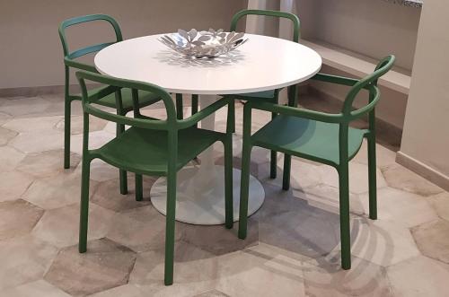 a white table and four green chairs on a tile floor at Appartamento Pertinace Centro Storico Alba in Alba