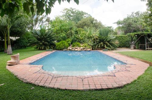 a swimming pool in a yard with a brick patio at Hillside Manor in Bulawayo