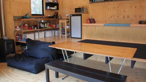 a kitchen with a table and a black couch at BAY OF FIRES ECO HUT off grid experience at Binalong Bay in Binalong Bay