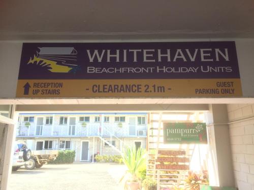 a street sign on a pole in front of a store at Whitehaven Beachfront Holiday Units in Airlie Beach