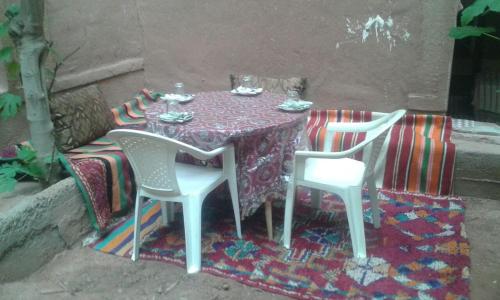 a table with two white chairs and a purple tablecloth at Riad Berbère Boutaghrar in Bou Tharar