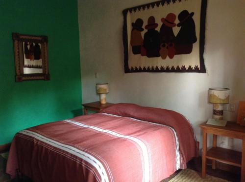 a green bedroom with a bed and a painting on the wall at Posada Yolihuani in Pátzcuaro