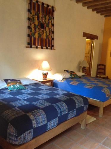 a bedroom with two beds and a lamp on a table at Posada Yolihuani in Pátzcuaro