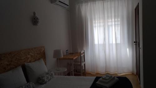 a bedroom with a bed and a window with a desk at Route 2 Torrão in Torrão