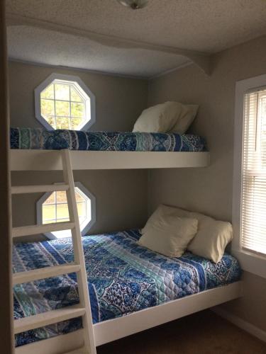 a bedroom with two bunk beds and two windows at Rappahannock River Cottage Near I-95! in Fredericksburg
