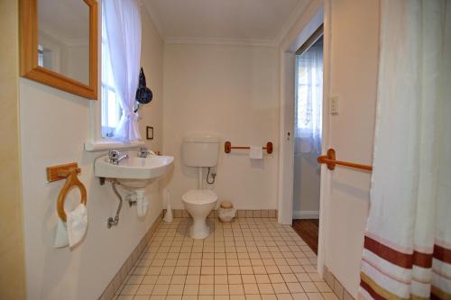 a bathroom with a toilet, sink, and bathtub at Rosedale Cottages in Taranna