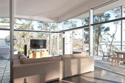 a living room with a couch and a tv at Baragoola Retreat - Luxury Waterfront Property in Sandford