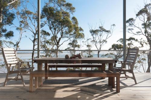 a wooden picnic table and two chairs on a deck at Baragoola Retreat - Luxury Waterfront Property in Sandford