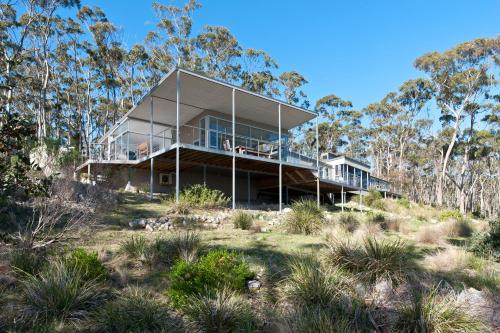 a house on top of a hill with trees at Baragoola Retreat - Luxury Waterfront Property in Sandford