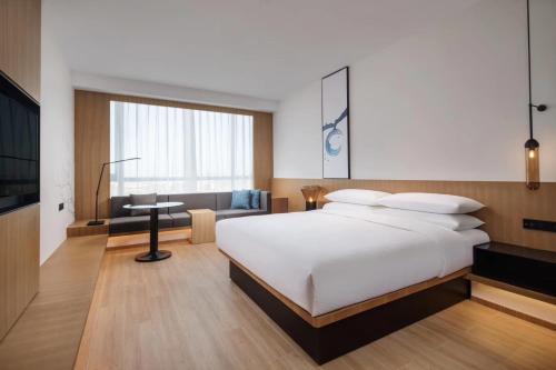 Schlafzimmer mit einem großen weißen Bett und einem Schreibtisch in der Unterkunft Fairfield by Marriott Guangzhou Tianhe Park in Guangzhou