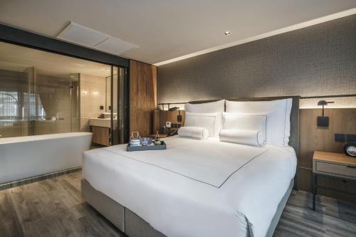 a bedroom with a large white bed and a bath tub at Tastoria Collection Sukhumvit - SHA Extra Plus in Bangkok