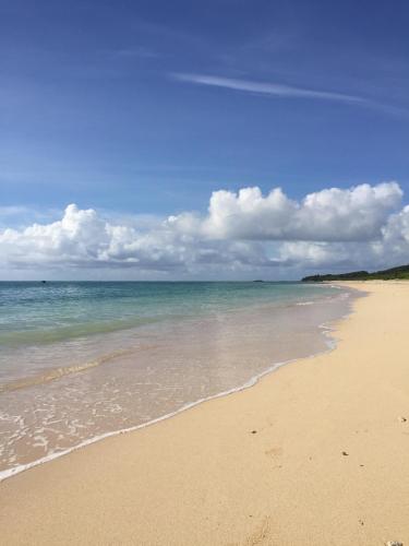 a sandy beach with the ocean and clouds in the sky at guest house annsea in Ishigaki Island