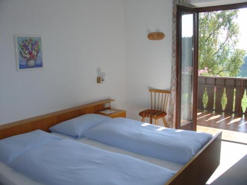 a bed with blue sheets in a bedroom with a balcony at Haus Hafner in Avelengo