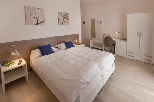 a bedroom with a large white bed with blue pillows at Hotel Roma Aparthotel in Malcesine