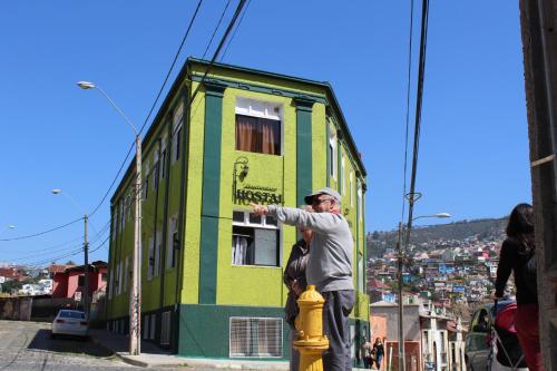 un uomo in piedi su un idrante antincendio di fronte a un edificio di Hostal Dinamarca a Valparaíso
