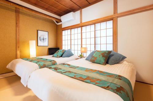 two beds in a room with two windows at Suiren Residential Suite Tokyo in Tokyo