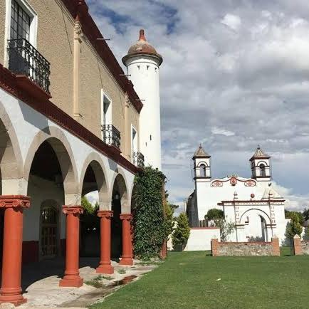 a building with two white towers in a yard at Ex-Hacienda San Buenaventura in San Lorenzo Soltepec