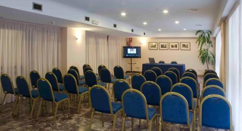 a conference room with blue chairs and a podium at Hotel Leuka in Alicante