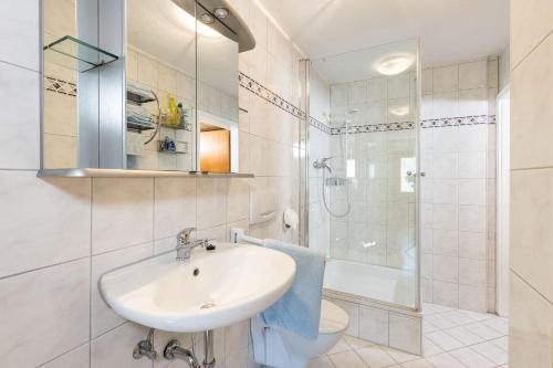 ein weißes Bad mit einem Waschbecken und einer Dusche in der Unterkunft Landhaus Breg in Hergensweiler