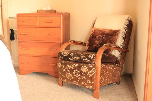 a chair in a bedroom with a dresser and a drawer at Waipoua Lodge in Donnellys Crossing