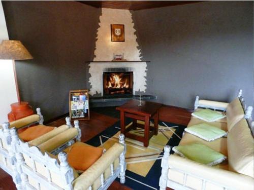 a living room with chairs and a fireplace at Hotel Vill' Agi in Campos do Jordão