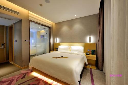ein Hotelzimmer mit einem großen Bett und einer ebenerdigen Dusche in der Unterkunft Lavande Hotel Shanghai Jiading Xincheng Stadium Branch in Jiading