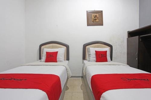 two beds in a room with red pillows at RedDoorz @ Soekarno Hatta 2 in Malang