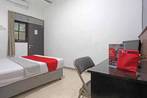 a bedroom with a bed and a desk with a chair at RedDoorz @ Soekarno Hatta 2 in Malang