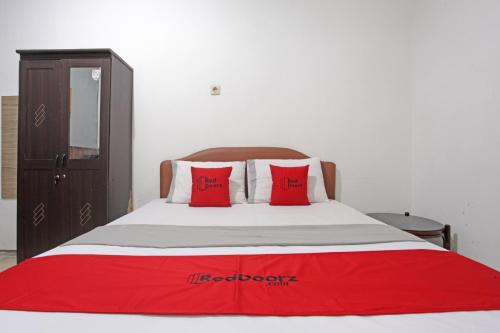 a bedroom with a bed with red pillows on it at RedDoorz @ Soekarno Hatta 2 in Malang