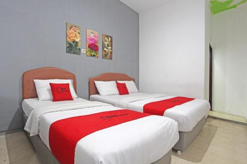 two beds in a room with red and white sheets at RedDoorz @ Soekarno Hatta 2 in Malang
