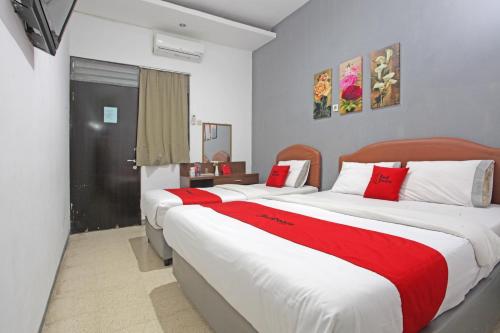 two beds in a room with red and white sheets at RedDoorz @ Soekarno Hatta 2 in Malang