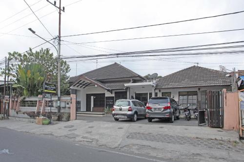 two cars parked in a parking lot in front of houses at RedDoorz @ Soekarno Hatta 2 in Malang