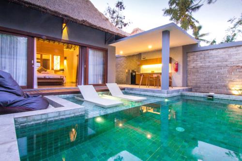 a swimming pool with two chairs and a house at A Villa Gili Air in Gili Islands