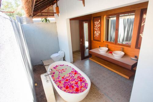 A Villa Gili Air في غيلي آير: حمام مع حوض استحمام مغطى بالرشات