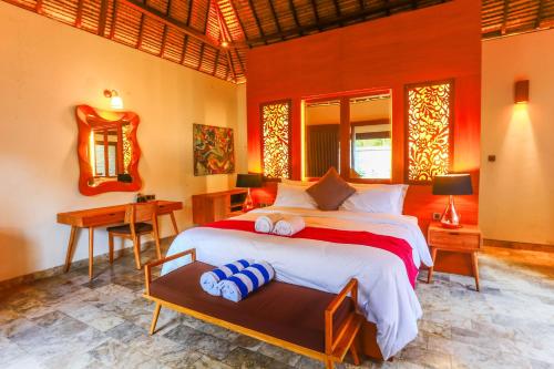 a bedroom with a large bed and a desk at A Villa Gili Air in Gili Air