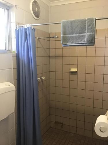 a bathroom with a shower with a blue shower curtain at Rankins Springs Motel in Rankins Springs