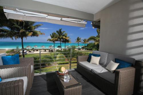 a patio with a couch and a view of the beach at Paradise Beach Luxury Beachfront Apartment Pointe d'Esny in Pointe d'Esny